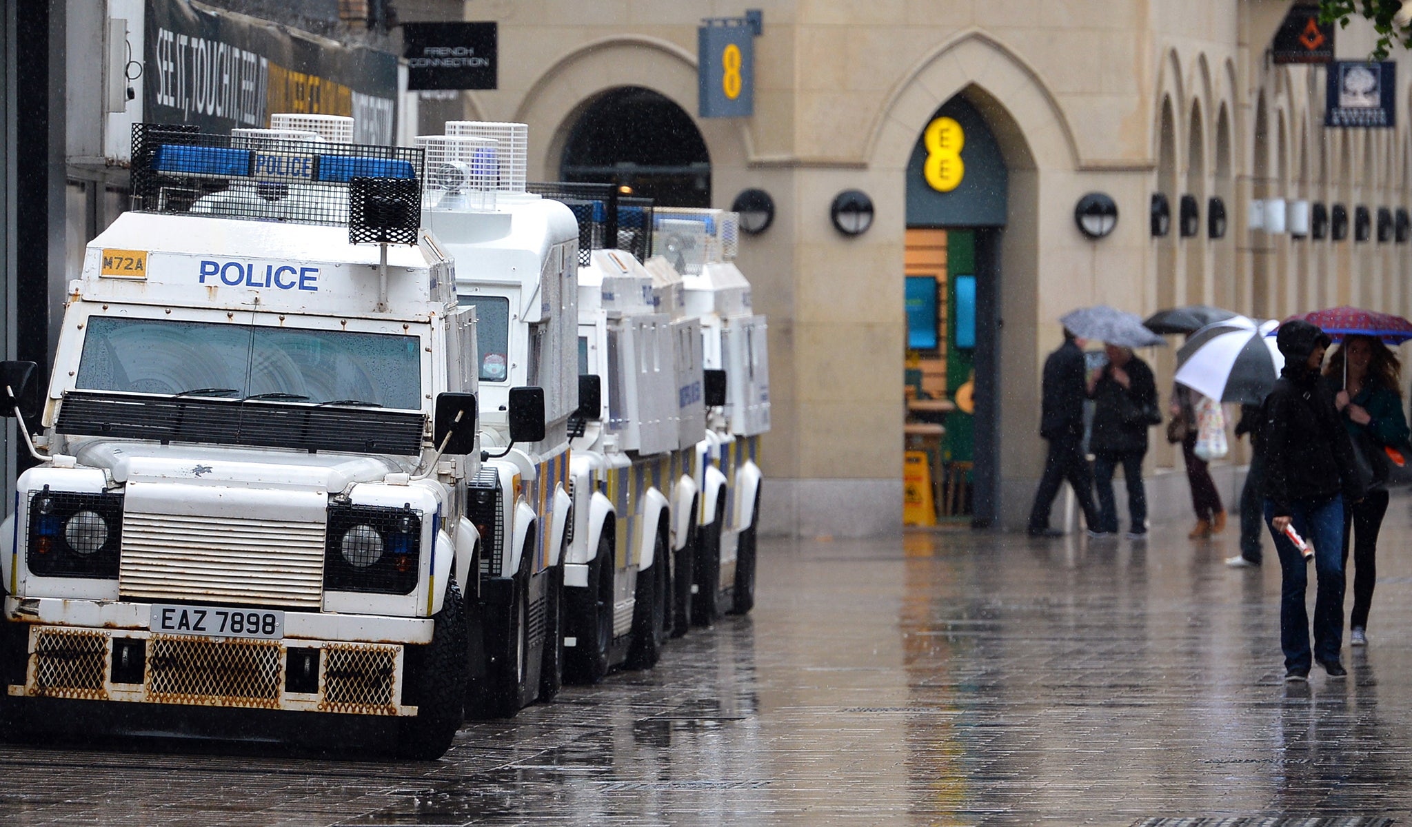 Shoppers walk past armoured police vehicles in Belfast city centre in June 2013