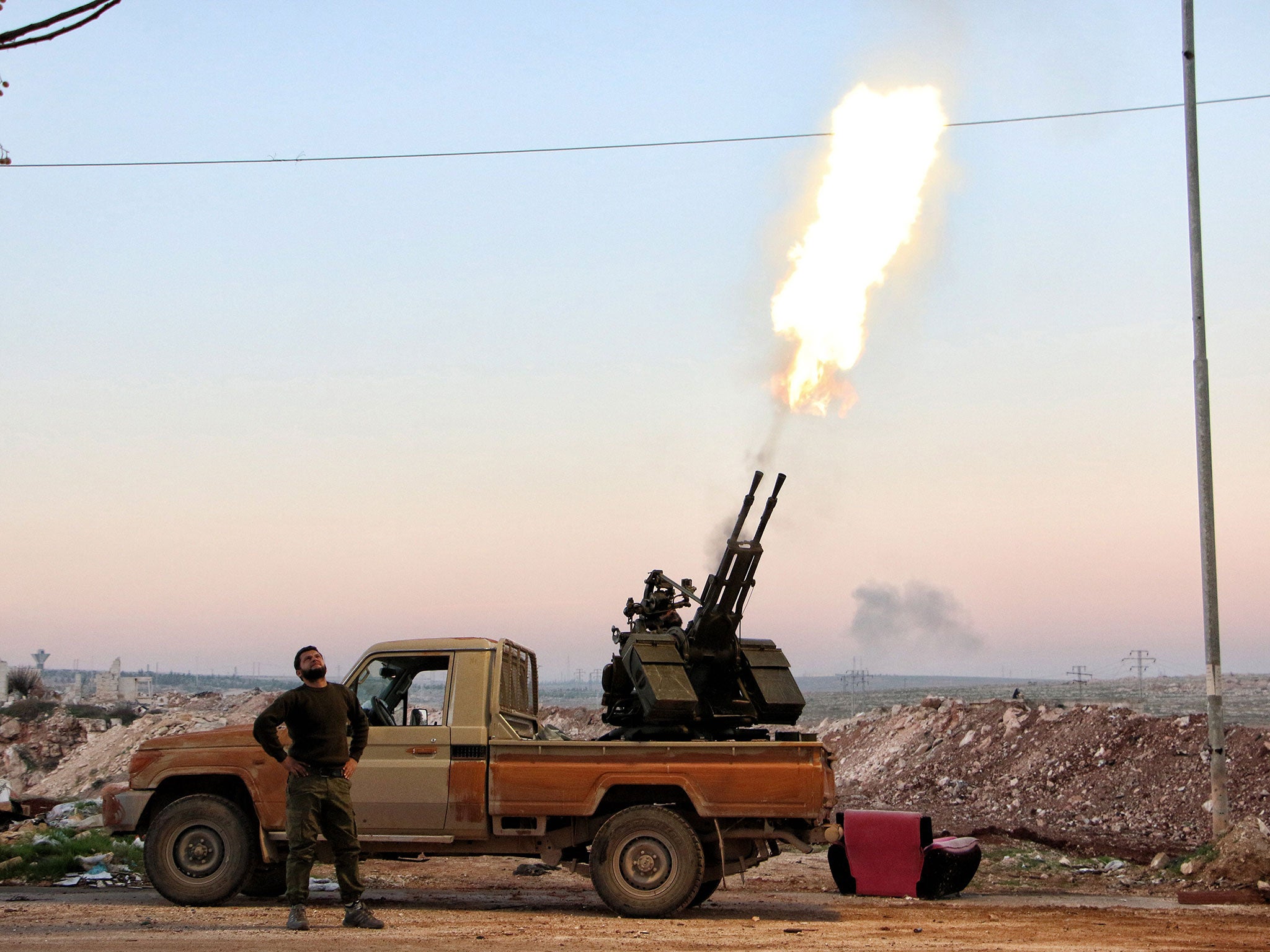 Opposition fighters fire a heavy machine gun towards government forces helicopters reportedly dropping barrel bombs near the northern Syrian city of Aleppo