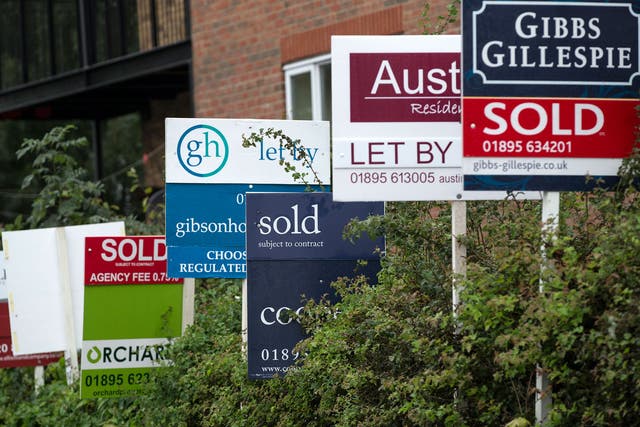 A row of estate agent boards are placed outside sold and let properties