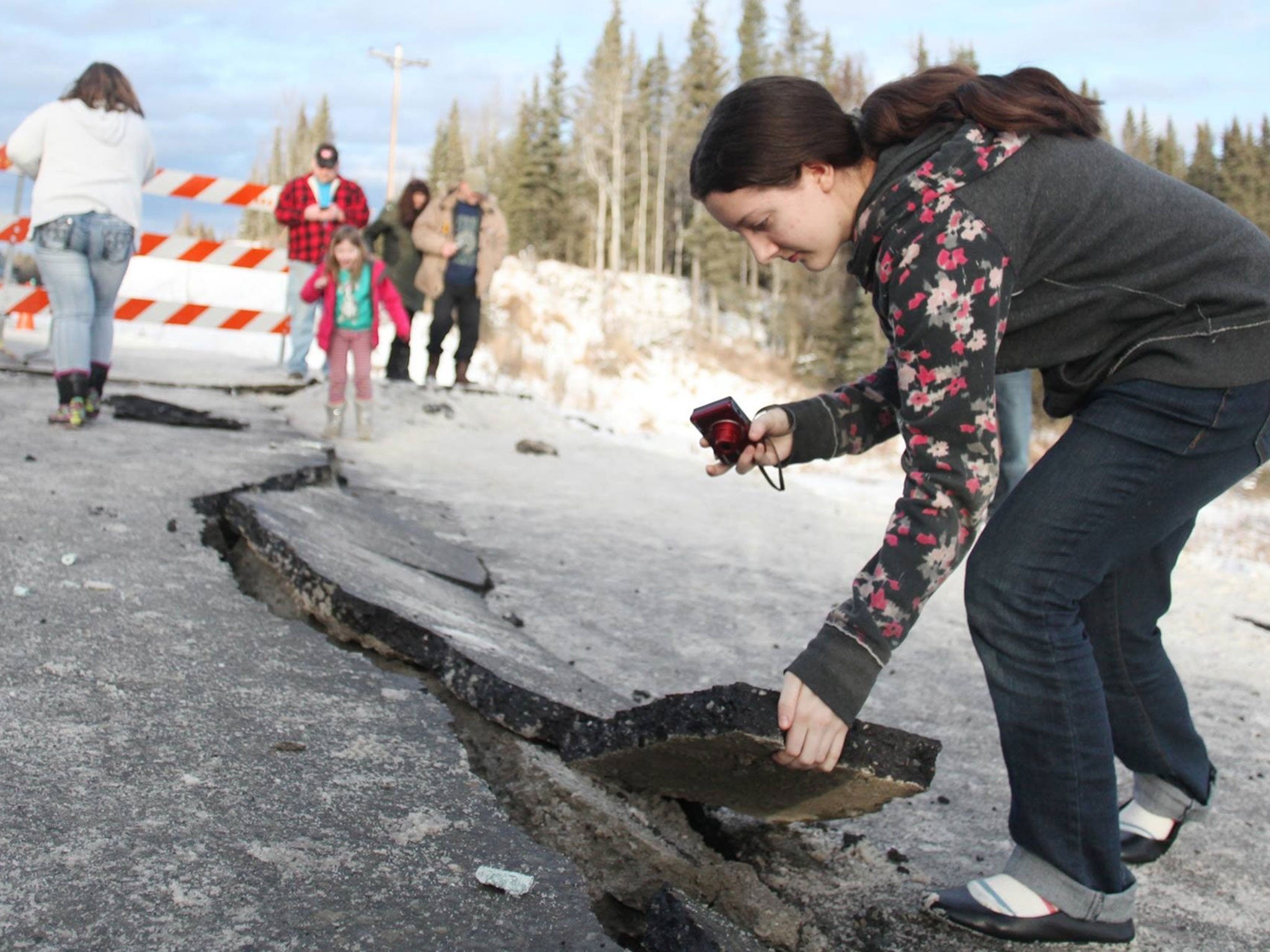 Tyrrel Corveia, 14, lifts a piece of the road surface along a crack in Kalifornsky-Beach Road near Kasilof, Alaska, Sunday, Jan 24, 2016