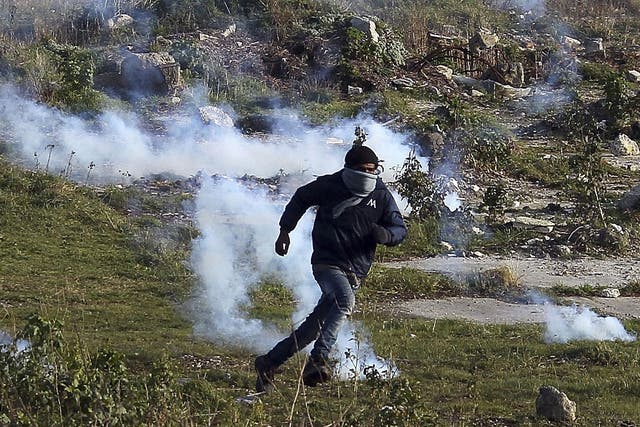 A migrant runs away from tear gas thrown by police forces near the Channel Tunnel in Calais
