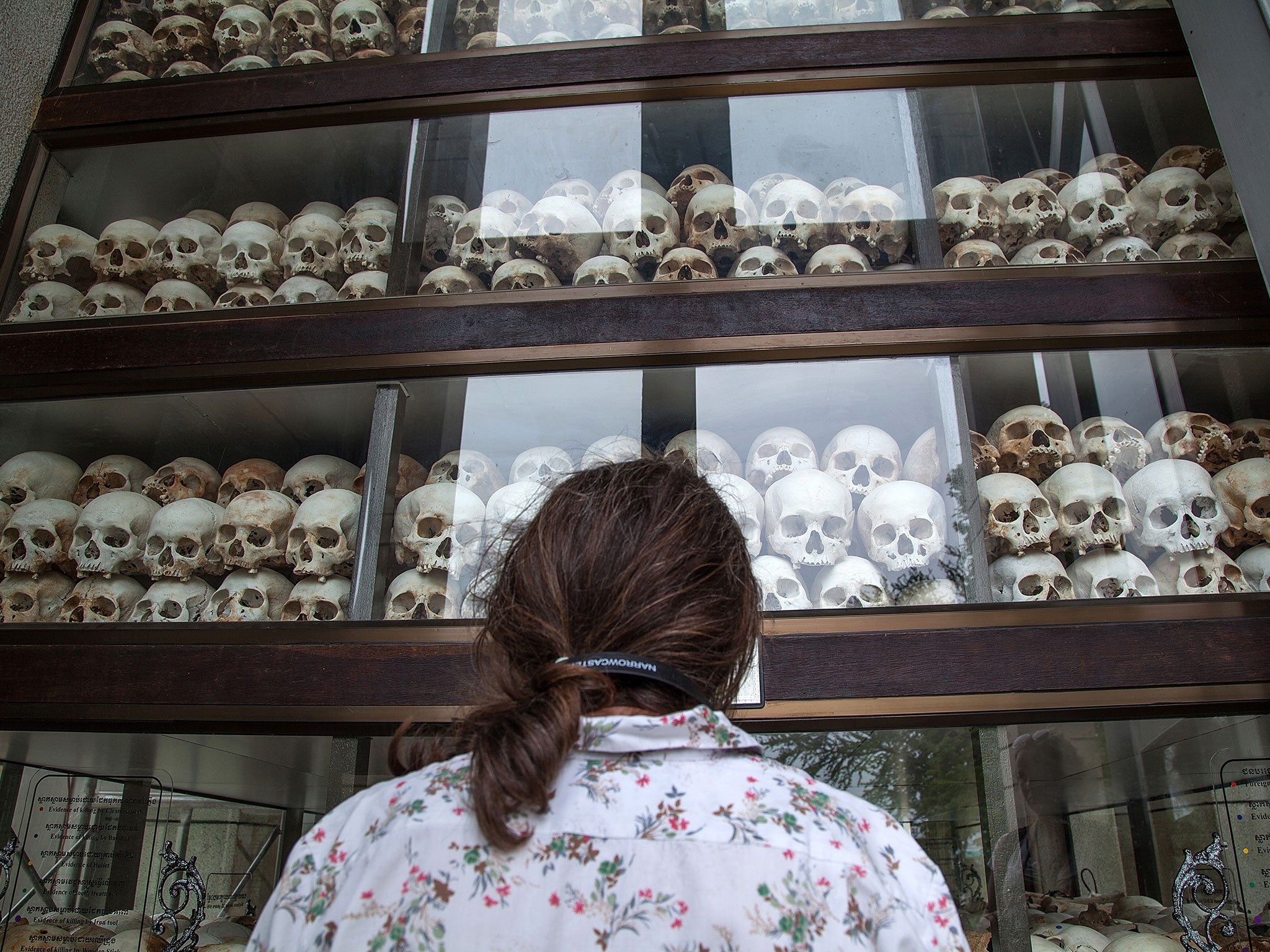 A young Cambodian woman looks at the main stupa in Choeung Ek Killing Fields, which is filled with thousands of skulls of those killed during the Pol Pot regime