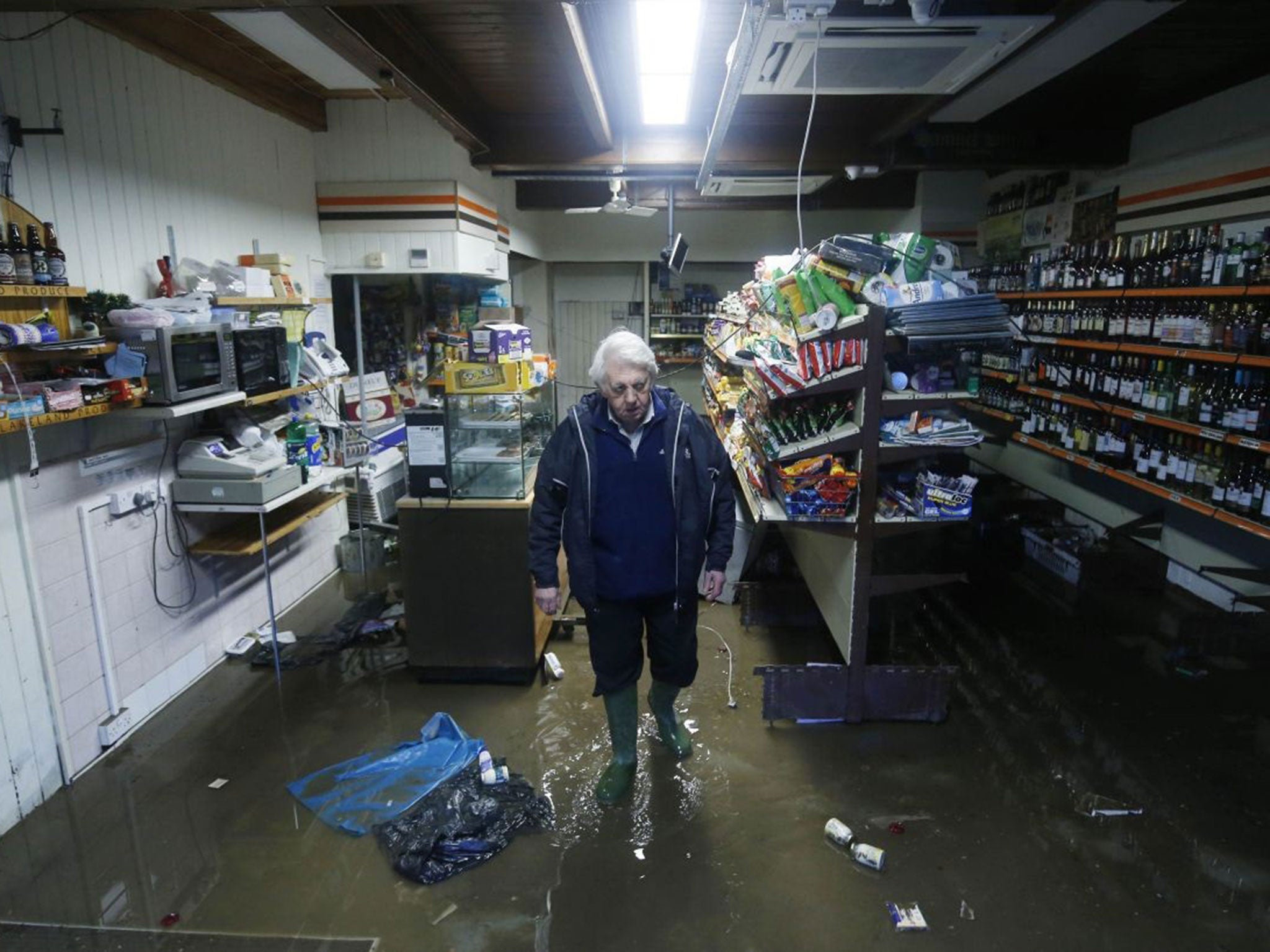 Allan John Brown looks at the damage caused to Glenridding Mini Market after the river in the town in Cumbria burst its banks in December