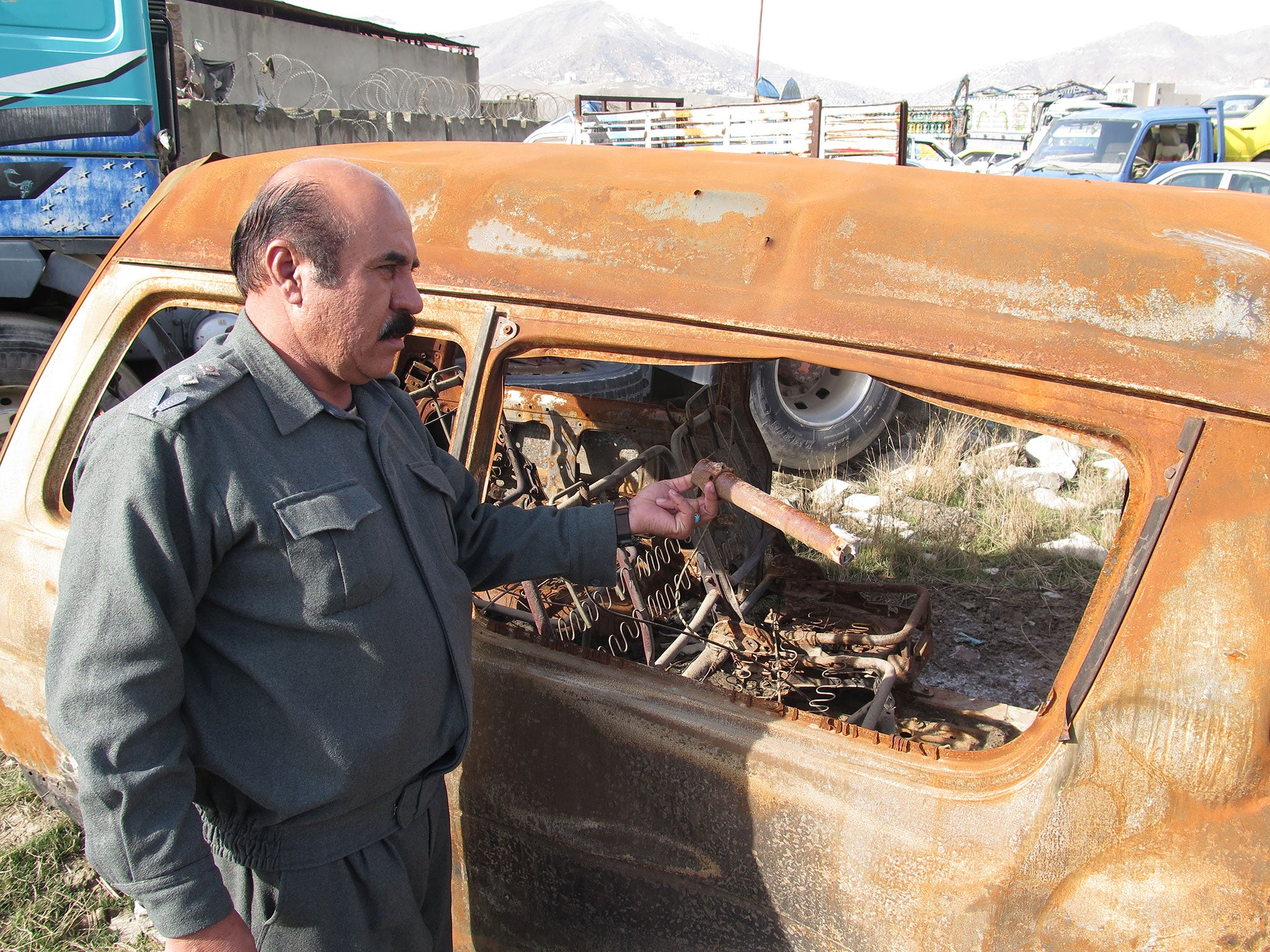 Miragha Gulbahari picks up a rocket-propelled grenade from a charred minivan used in a Taliban bomb attack