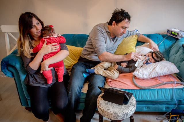 Serdar Agirman tending at home to his two-year-old son, Ruzgar, who has spinal muscular atrophy, alongside his wife Pelin and their baby daughter, Karia