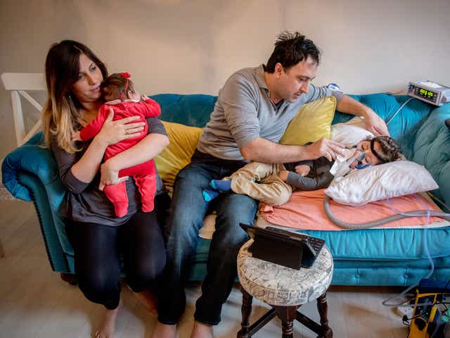 Serdar Agirman tending at home to his two-year-old son, Ruzgar, who has spinal muscular atrophy, alongside his wife Pelin and their baby daughter, Karia