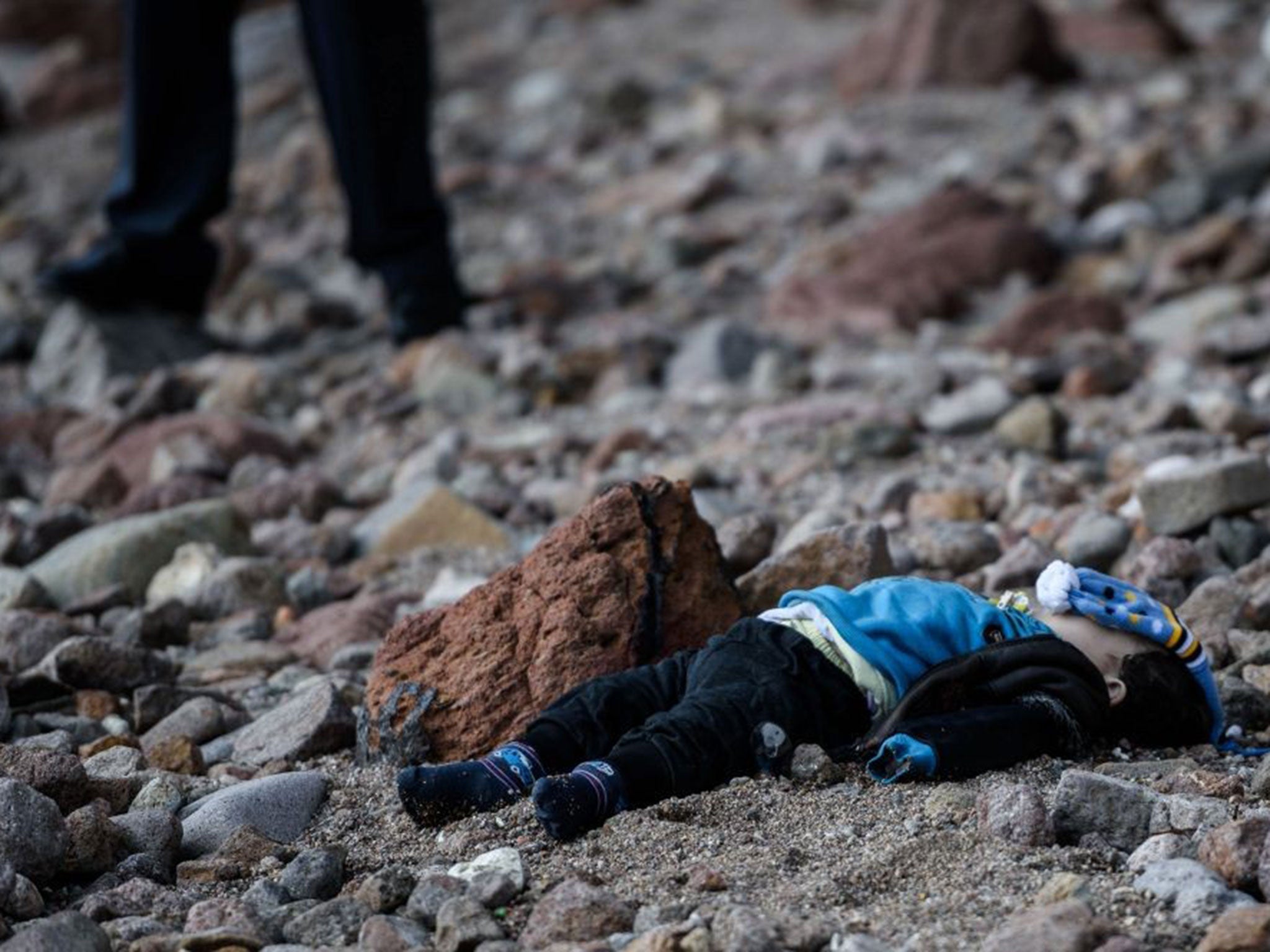 A man stands by the body of a refugee child washed up on a beach in Canakkale's Bademli district on January 30, 2016