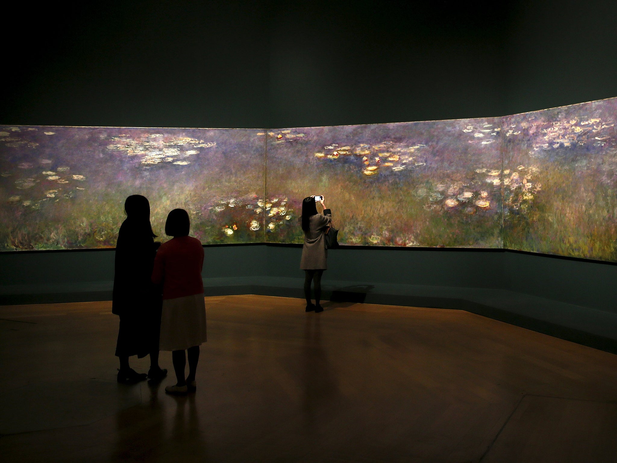 Visitors admire Claude Monet’s ‘Agapanthus Triptych’ at the Royal Academy of Arts