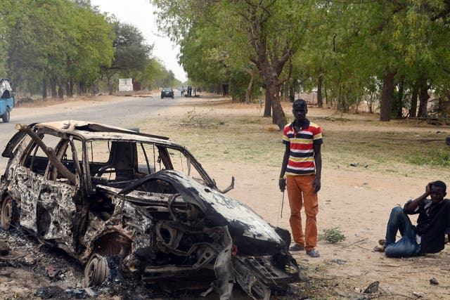 Two men next to a burnt out car in Maiduguri after a bomb attack by Boko Haram