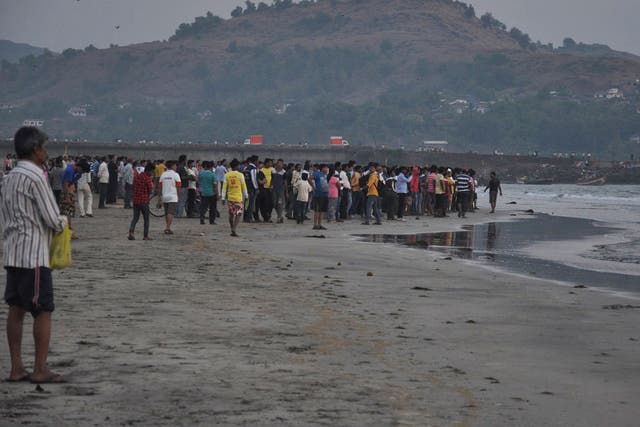 People gather on the beach after more than a dozen college students were swept away at Murud on the Arabian Sea coast about 150 kilometers (95 miles) south of Mumbai