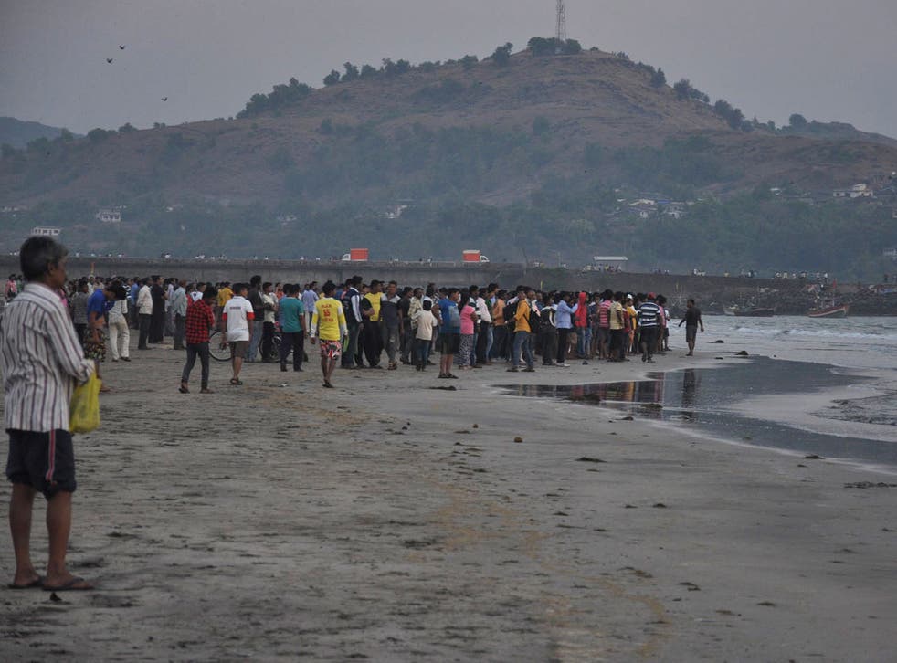 People gather on the beach after more than a dozen college students were swept away at Murud on the Arabian Sea coast about 150 kilometers (95 miles) south of Mumbai