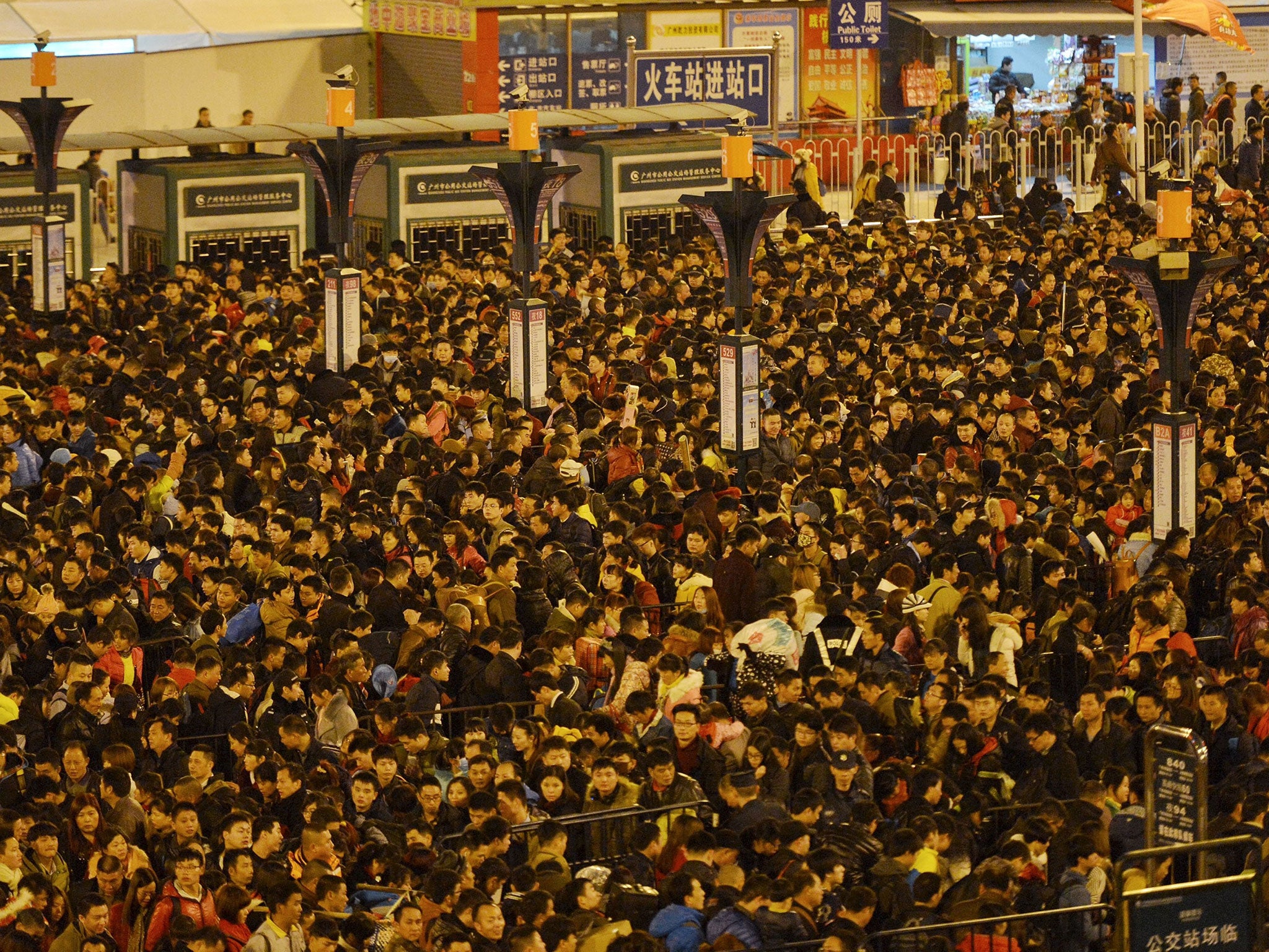 Passengers wait to enter a railway station after trains were delayed due to bad weather in southern China in Guangzhou