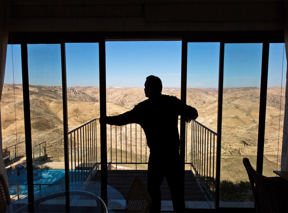 Igal Canaan closes the glass doors on his terrace overlooking Wadi Qelt at his bed and breakfast Nof Canaan