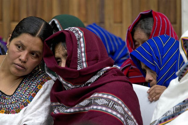 Alleged victims of sexual violence cover their faces as they listen to an interpreter on the first day of a trial against two former soldiers