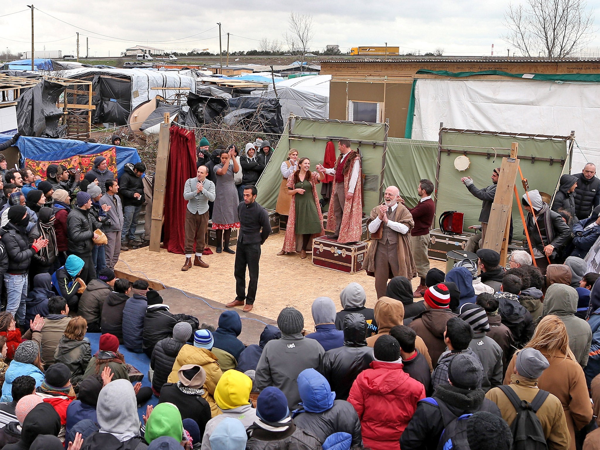 Residents of the Jungle, in Calais, gather to watch the Globe perform ‘Hamlet’ outside the Good Chance Theatre Tent