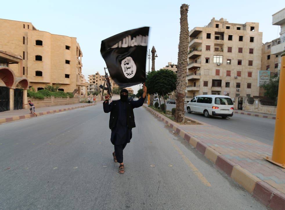 An Isis fighter in Syria waves the terrorist group's black flag