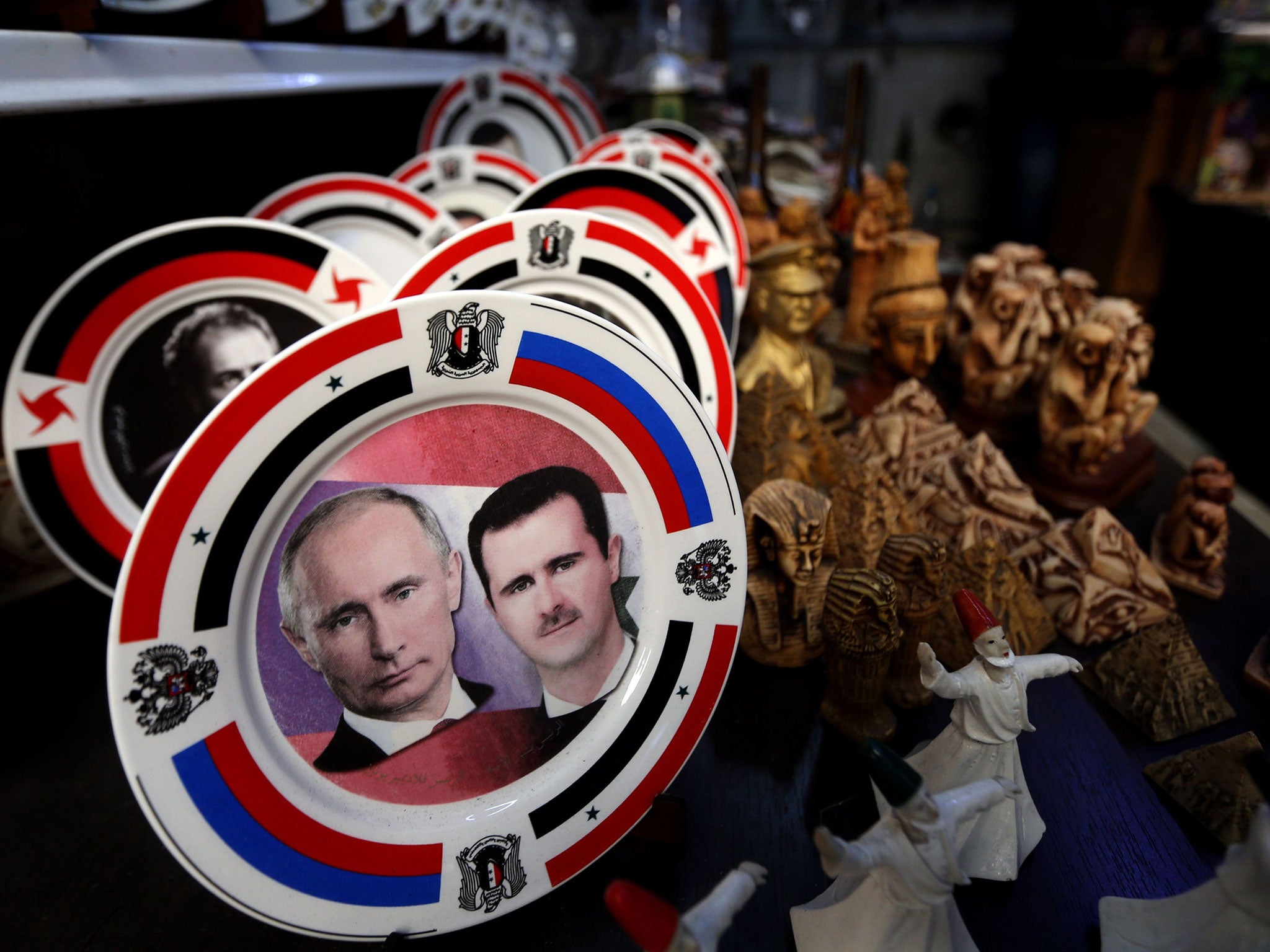 Porcelain plates bearing portraits of Syrian President Bashar al-Assad, right, and his Russian counterpart Vladimir Putin, left, are displayed at a handicrafts shop in the Syrian capital, Damascus