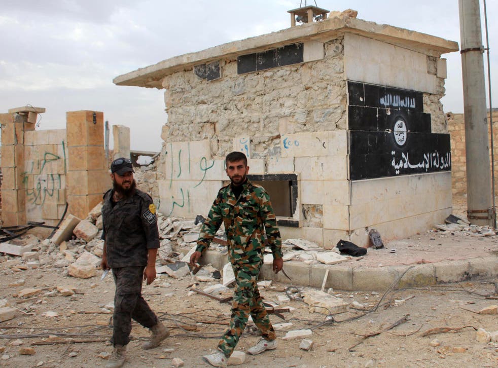 Government troops walk past Isis flag in recaptured Syrian town