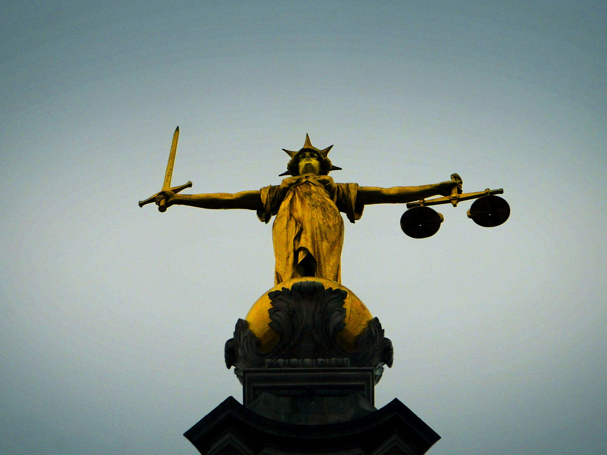 A statue of the scales of justice stands high above the Old Bailey