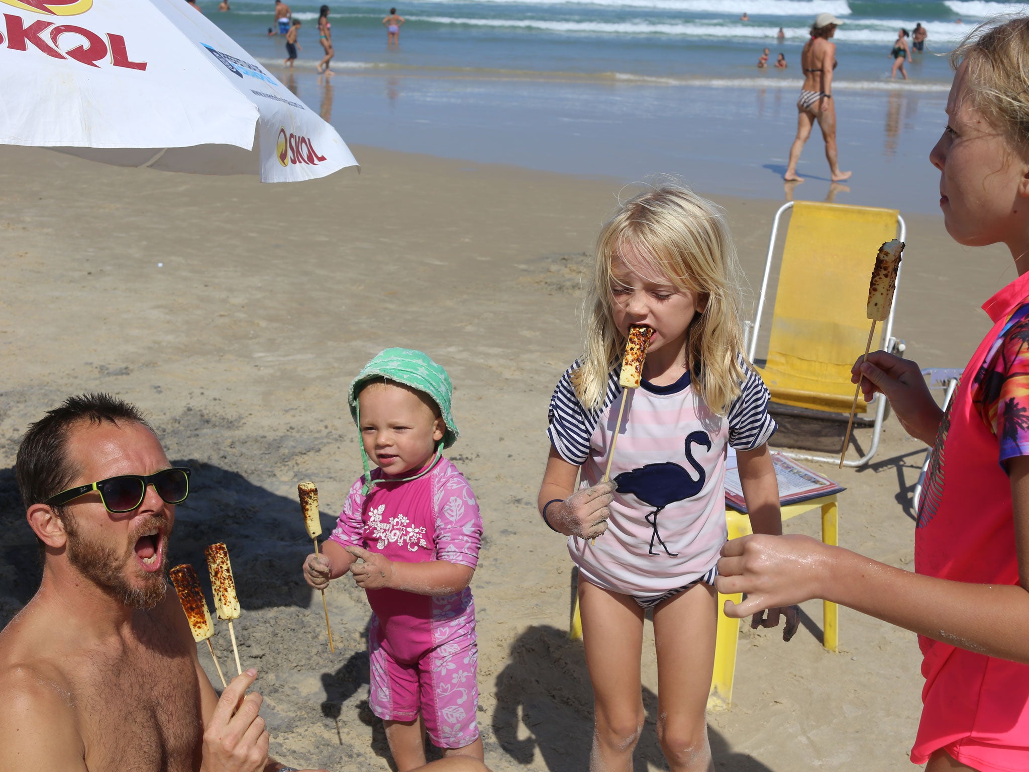 Cathy’s partner, Jason, and their three children eating beach food on Joaquina Beach, Florianopolis, Brazil