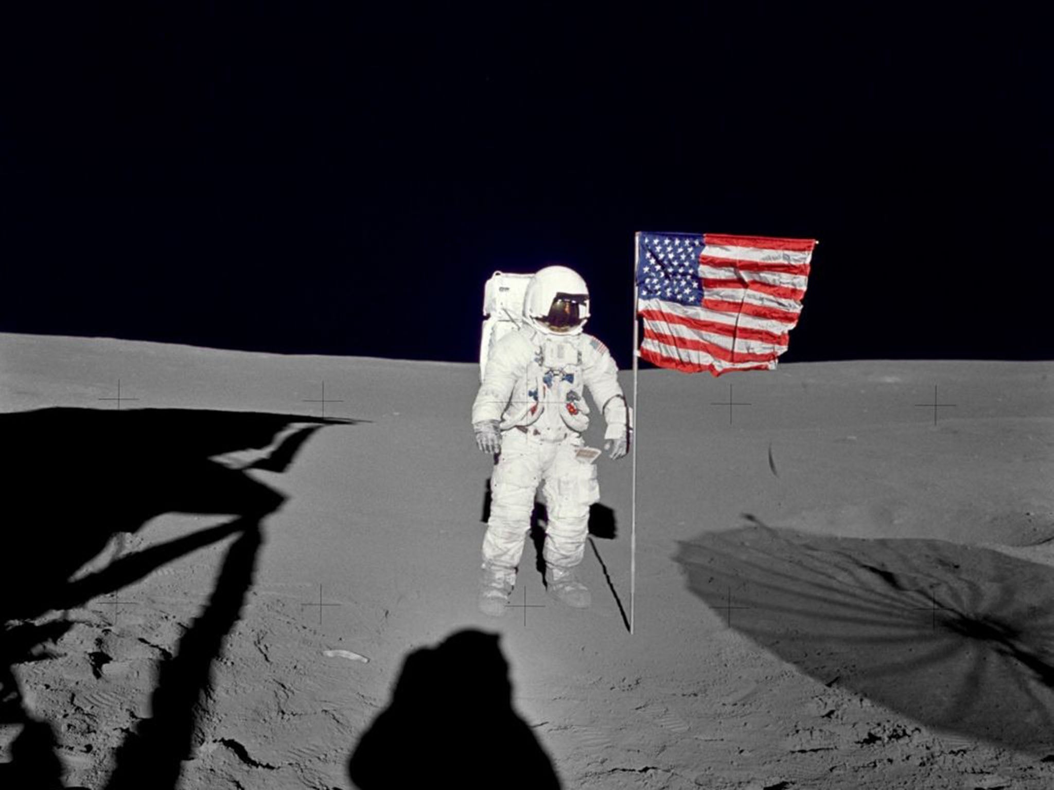 An undated photo showing Edgar Mitchell holding an American flag on the Moon