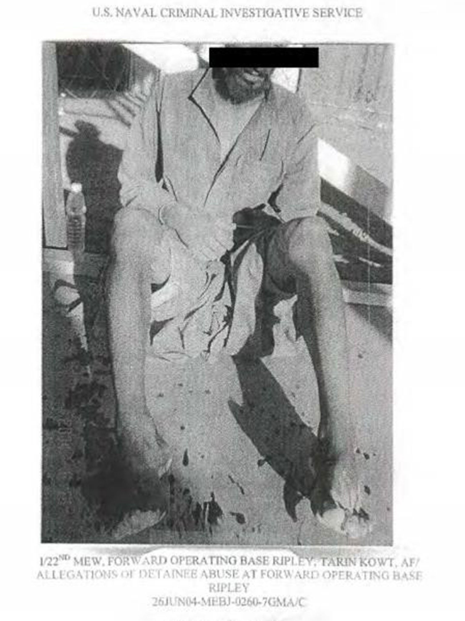 An alleged prisoner sitting in an evidence photo at an unknown location