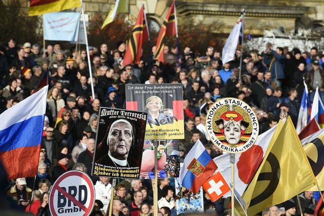 Supporters of the Pegida movement hold placards featuring Angela Merkel in Dresden, eastern Germany, on February 6, 2016