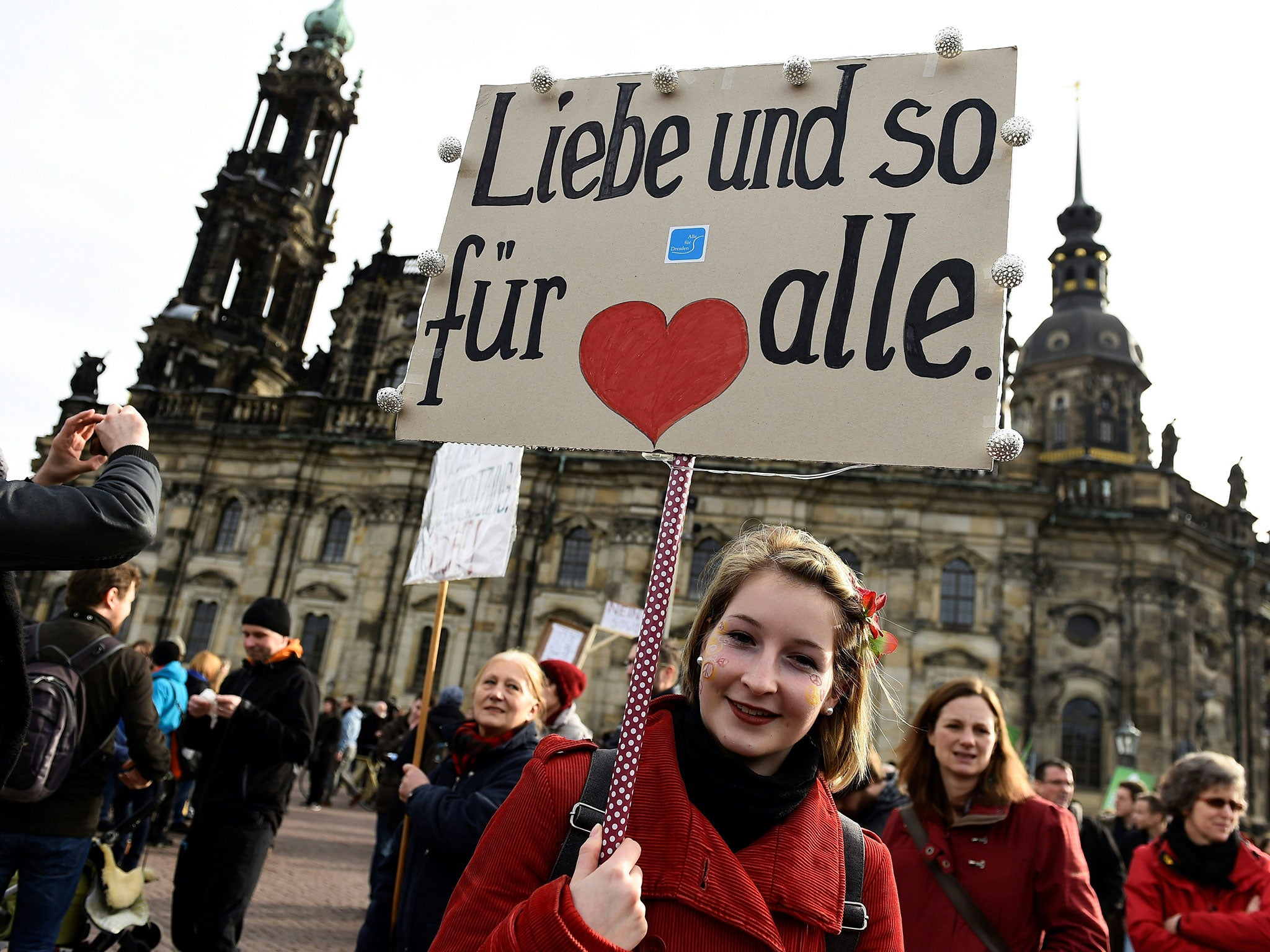 People gather in Dresden to protest against a mass rally of the Pegida movement with a placard reading 'Love for all' on February 6, 2016