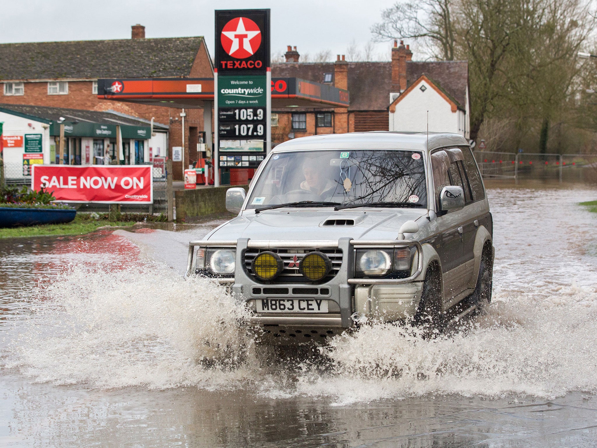 A 4x4 vehicle drives through flood water that has closed a road besides the River Severn in the town of Upton-upon-Severn