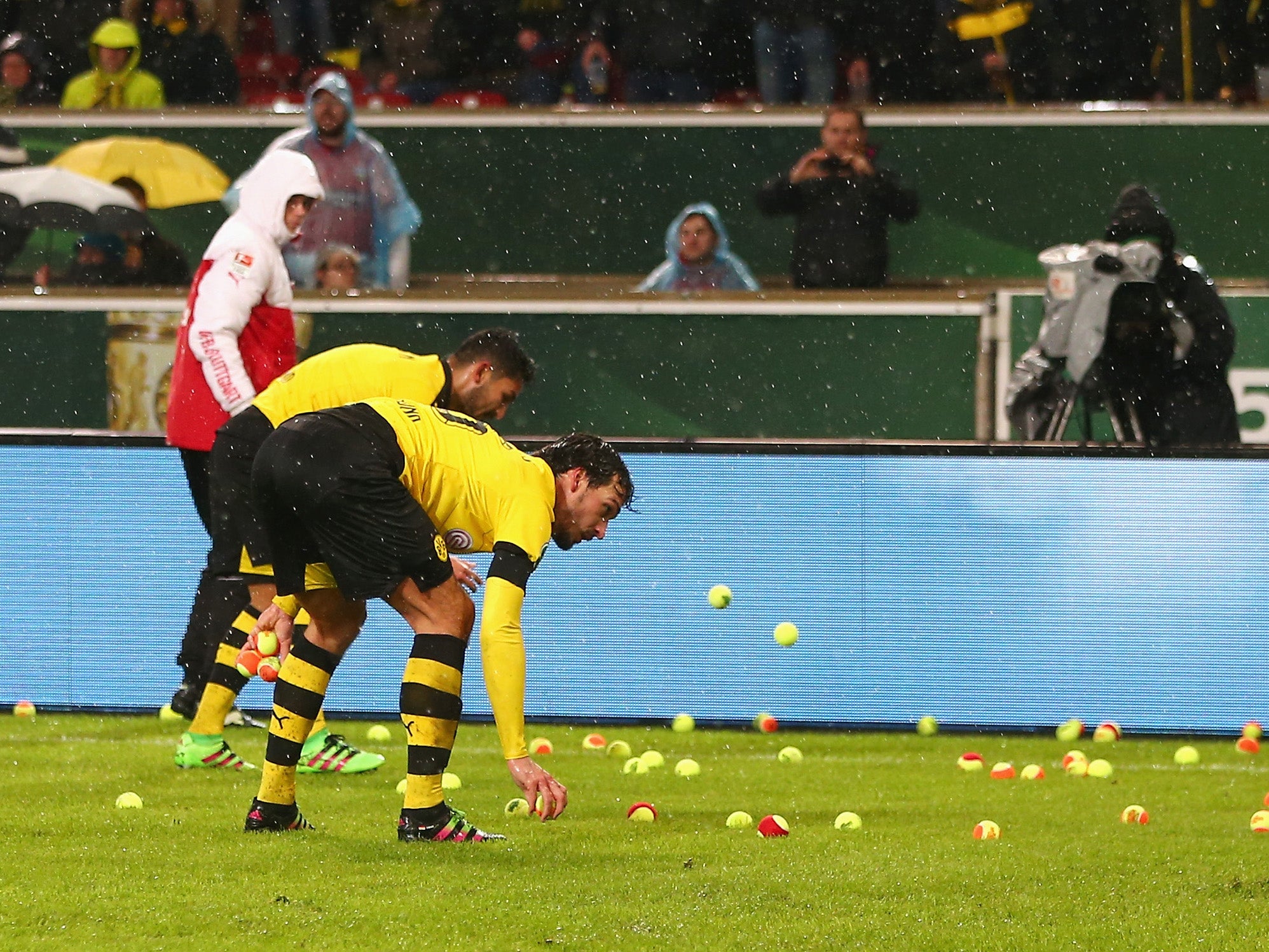 Borussia Dortmund players clear tennis balls from the pitch after a fans protest at Stuttgart