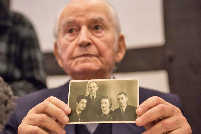 Leon Schwarzbaum at a press conference with a photograph of himself (left) with his uncle and parents, who died in Auschwitz