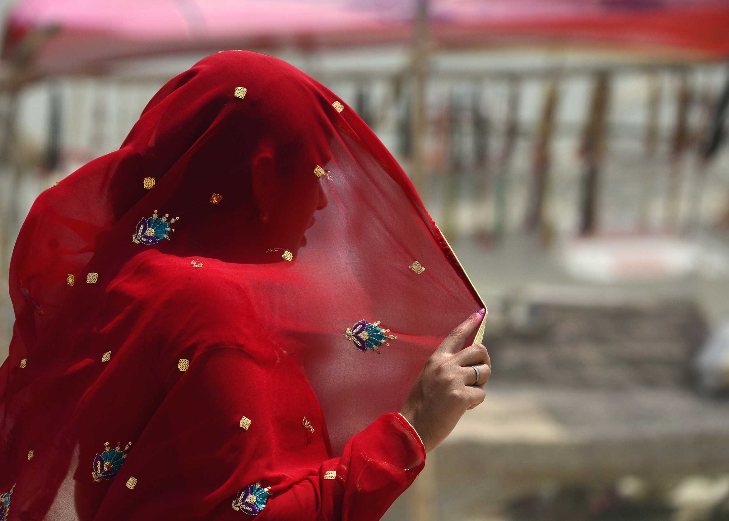 An Indian woman covers her face as she heads into a dust storm