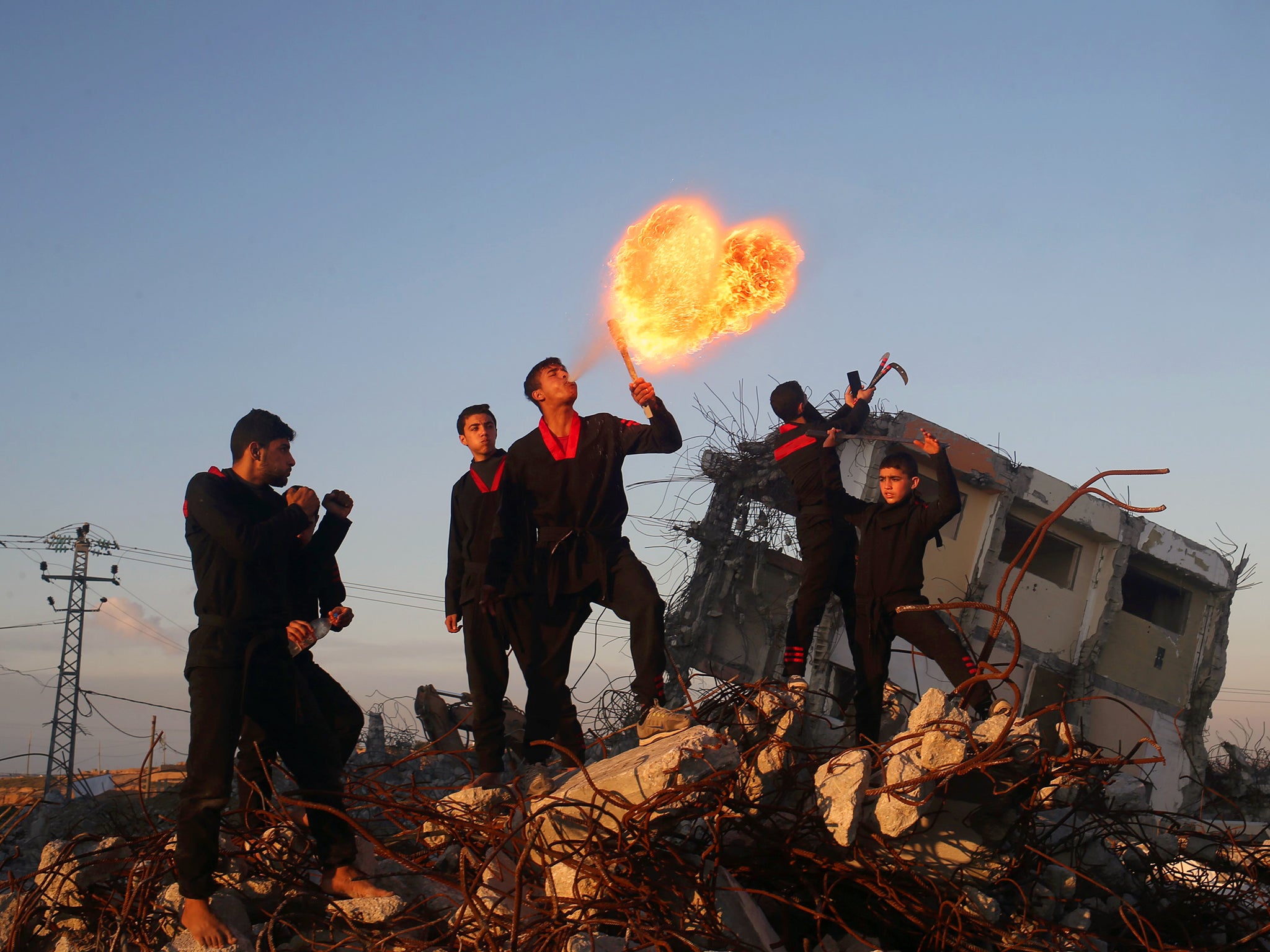 Palestinian youth, members of a Gazan martial art group, perform fire breathing at ruins of a house, that was destroyed in the 2014 war between Israel and Hamas militants, in Beit Hanoun in the northern Gaza Strip