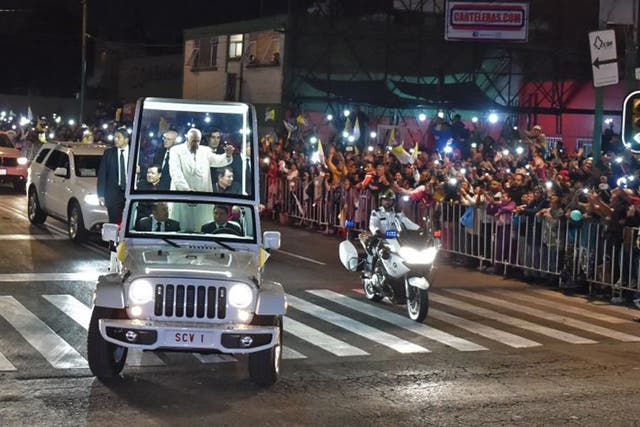 Pope Francis waves from his Popemobile as citizens flock to greet him in Mexico City