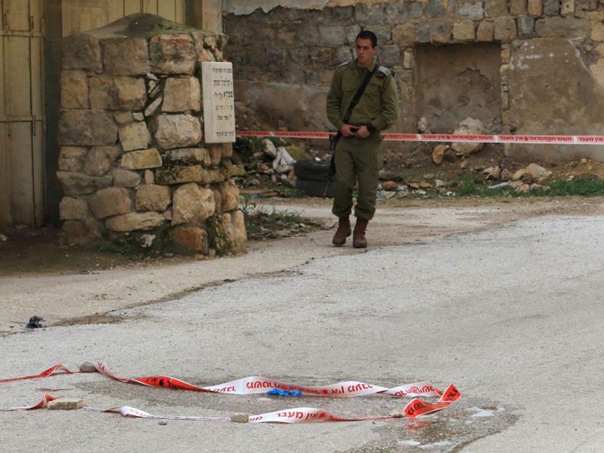 An Israeli security forces members monitors the site where a Palestinian woman tried to stab an Israeli soldier before being shot dead, in the Israeli occupied West Bank city of Hebron, on February 13, 2016.