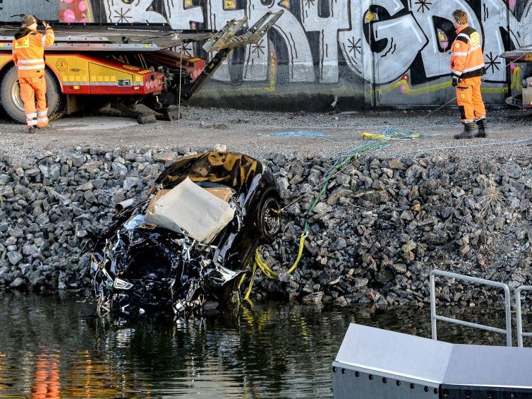 A badly damaged car is towed up from the canal under the E4 highway bridge in Sodertalje, Sweden,