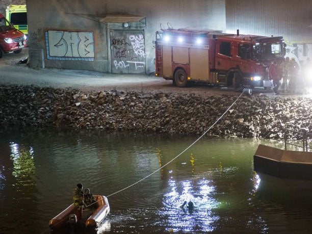 Divers and rescue service personnel search for the victims of the deadly car crash in the canal under the E4 highway bridge