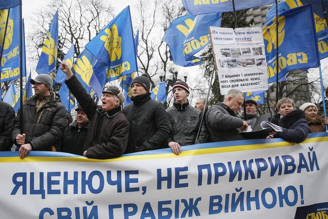 Supporters of nationalist Svoboda (freedom) party hold a banner reading 'Yatsenyuche do not hide your robbery by war' during a protest demanding the Ukrainian Prime Minister to step down