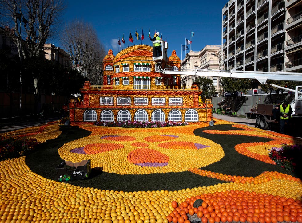 A worker puts the final touch to a sculpture made with lemons and oranges at the Lemon festival in Menton, France