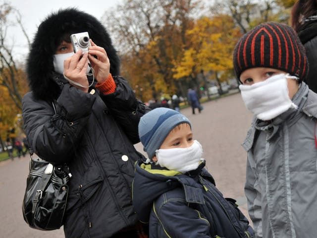 A woman and her children wear masks as they walk in the centre of western Ukrainian city of Lviv on October 30, 2009.