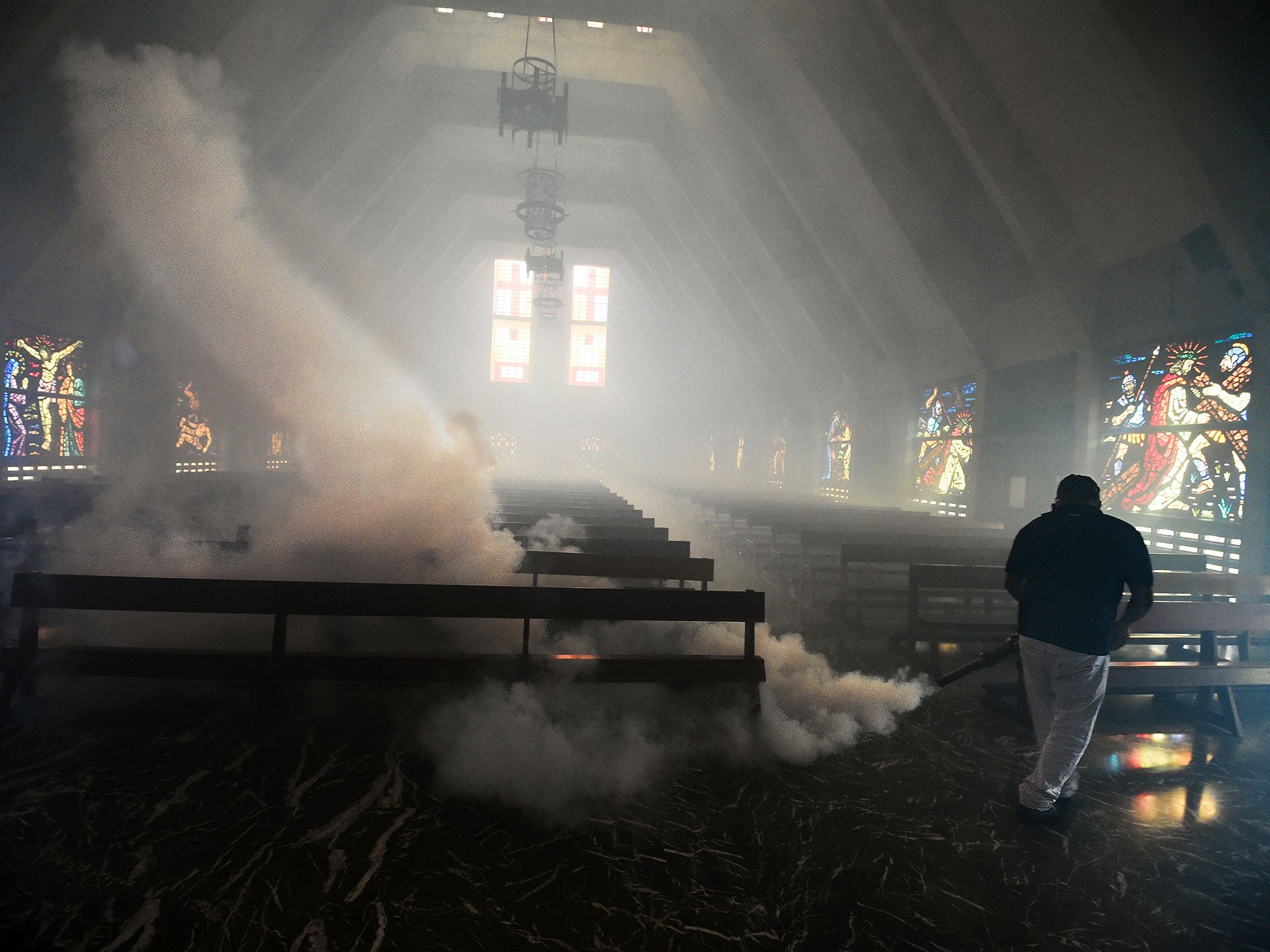 A Health Ministry employee fumigates against the Aedes Aegypti mosquito inside a church in Caracas on 5 February, 2016