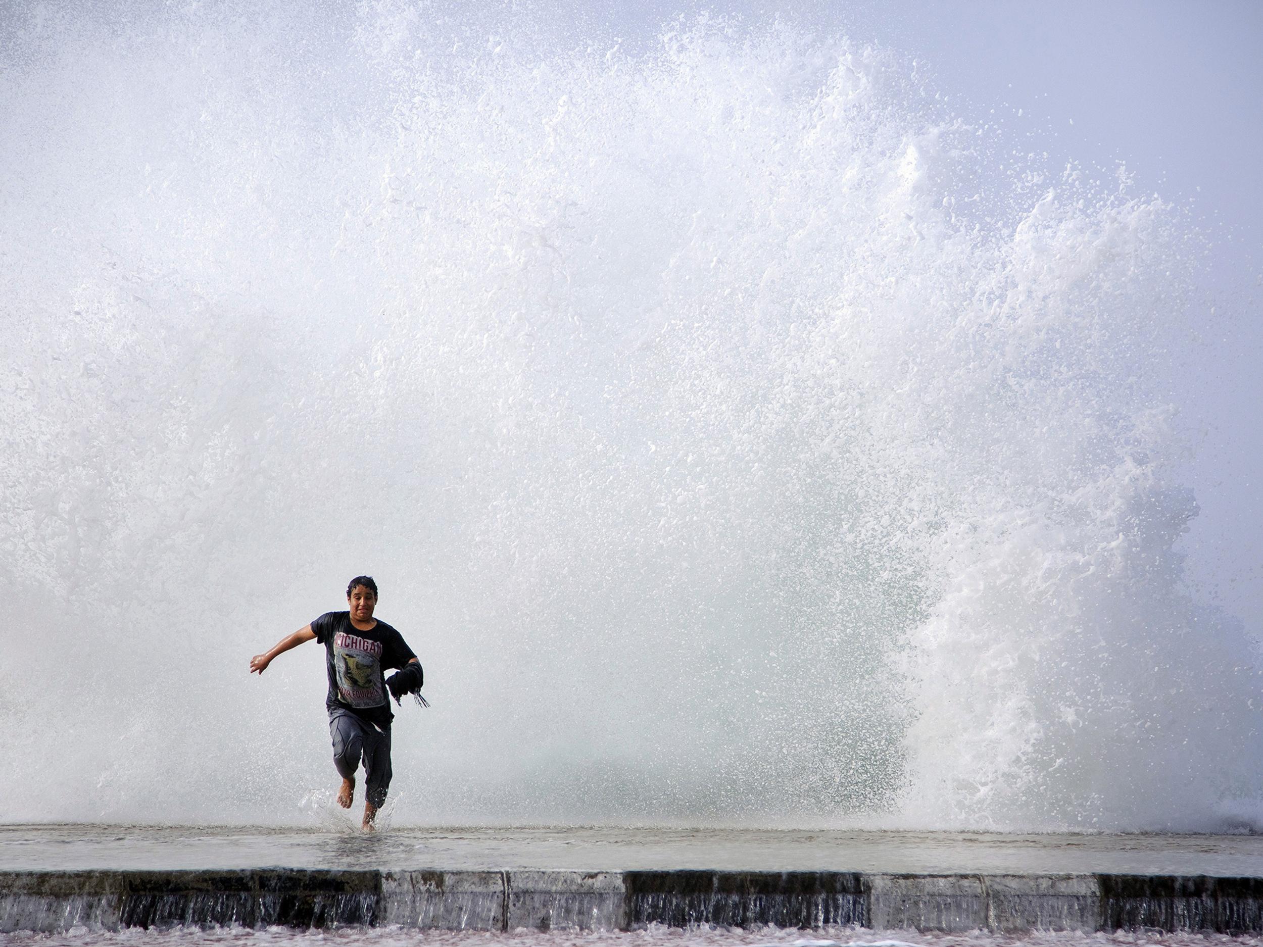 A Saudi man runs in front of a big wave as high winds batter the coast on February 11, 2015 in the Saudi Red Sea port city of Dhuba, located in Tabuk Province, northwest of the Saudi capital Riyadh.