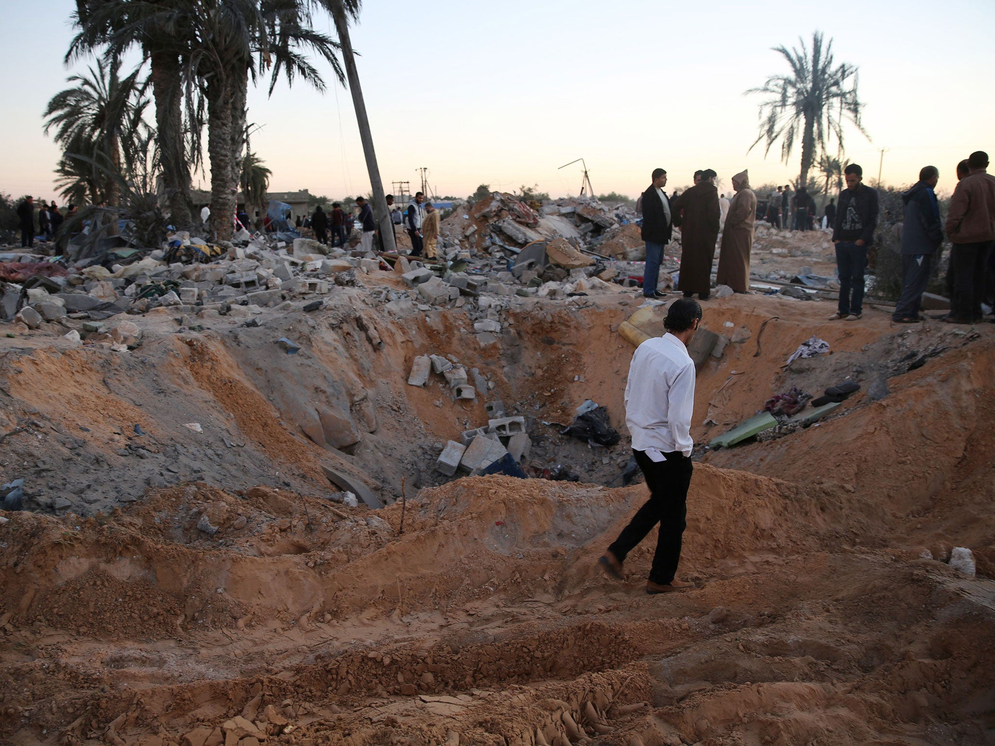 People gather after an air strike on a house and training camp belonging to the Islamic State group, west of Sabratha, Libya, on 19 February 2016