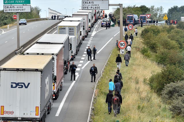 Police officers try to prevent migrants from climbing aboard trucks travelling to Britain, outside Calais last year