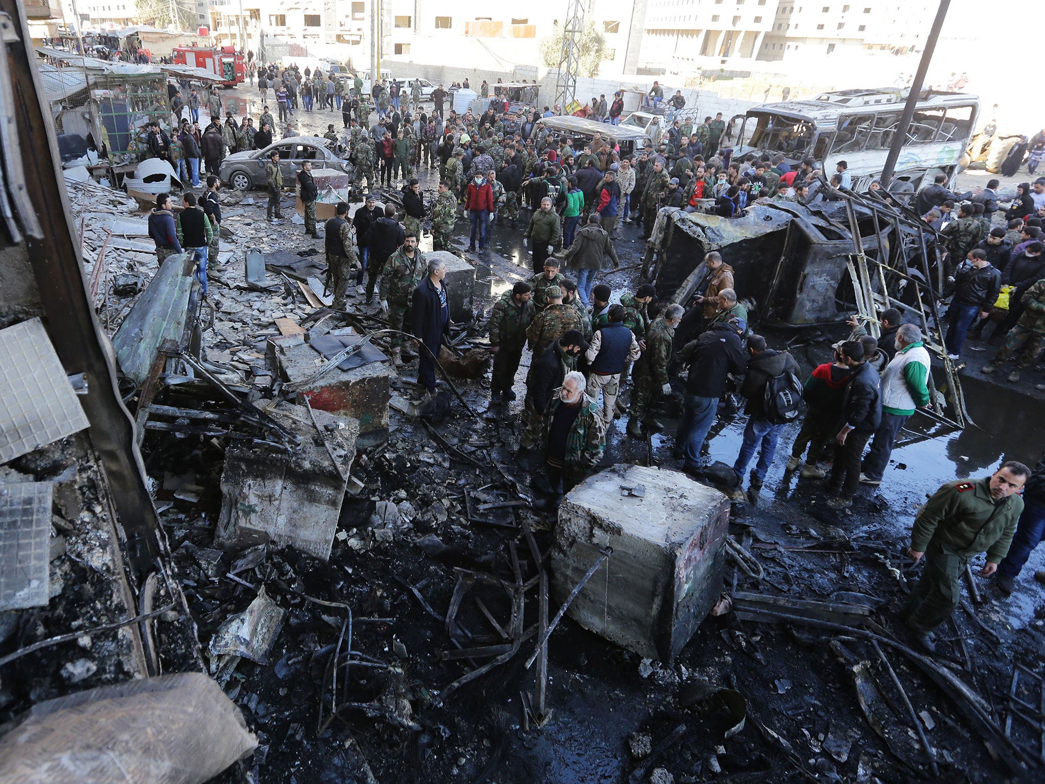 Syrian pro-government forces and residents gather at the site of previous suicide bombings in the area of a revered Shiite shrine in the town of Sayyida Zeinab, on the outskirts of the capital Damascus, on 31 January, 2016