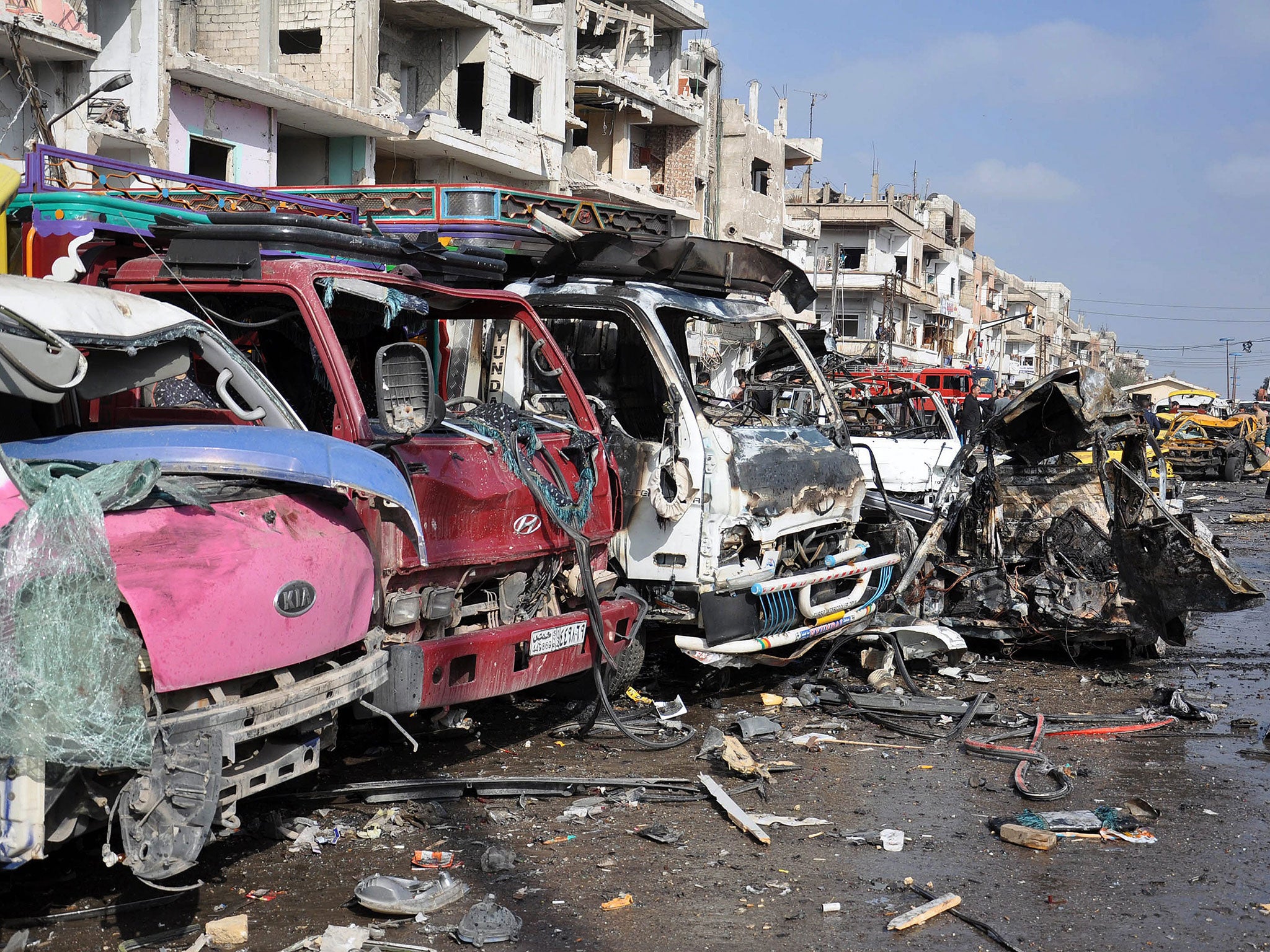 Wrecked buildings and vehicles at the site of twin car bombings that killed at least 57 people in the Syrian city of Homs