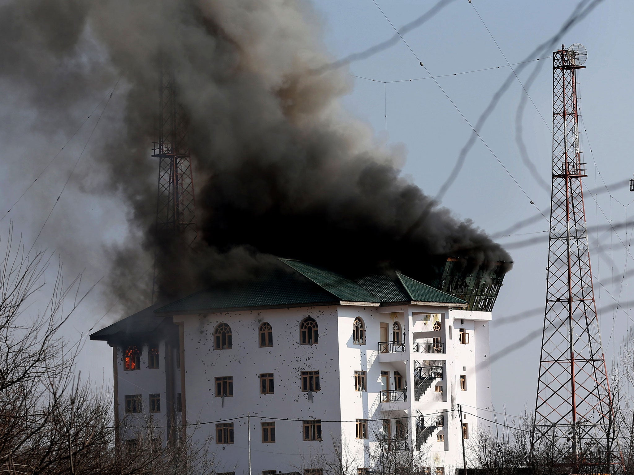 Smoke billows from a building where suspected militants have taken refuge during a gun battle on the outskirts of Srinagar, Kashmir