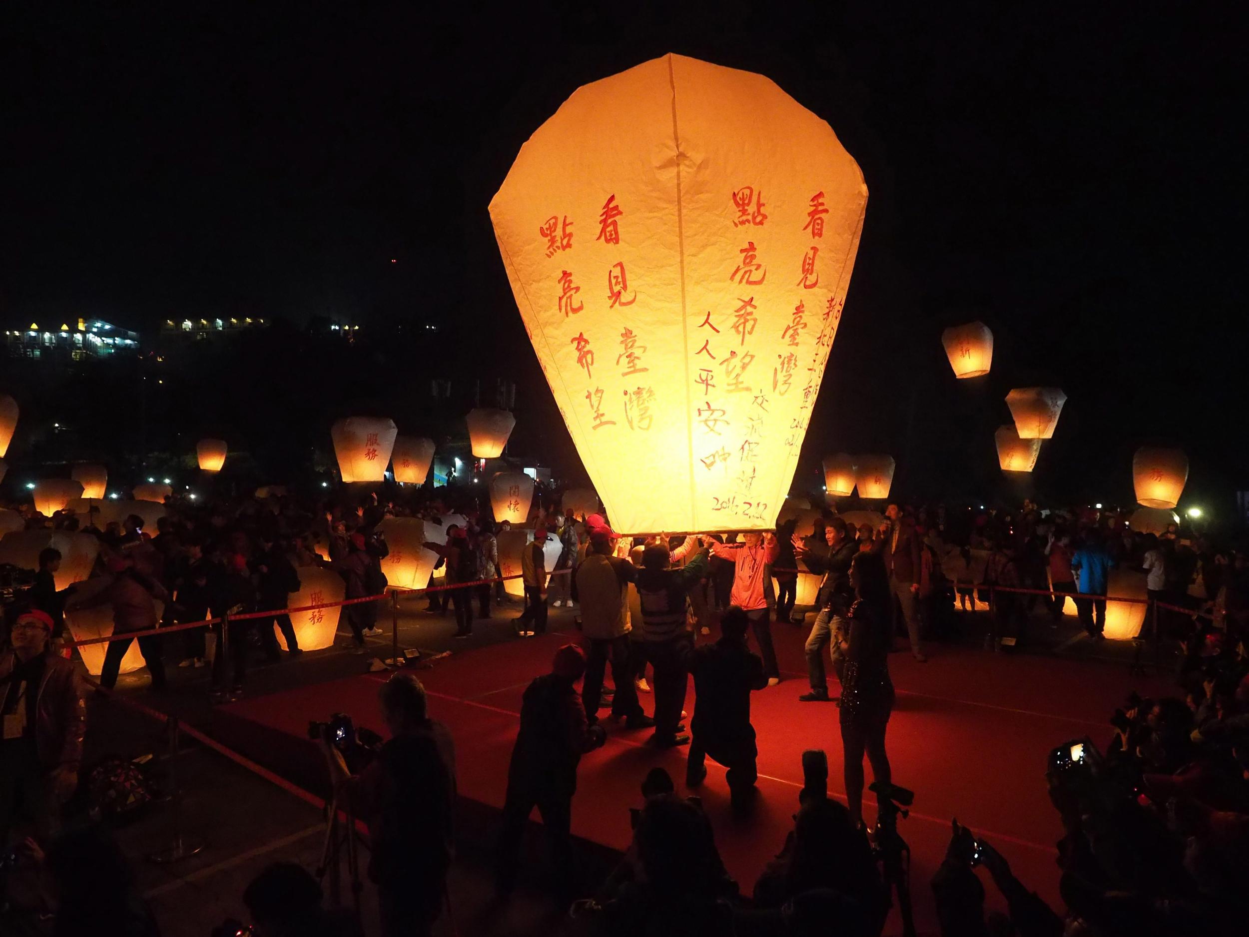 Taiwanese people release a giant sky lantern bearing the words 'Light Up'