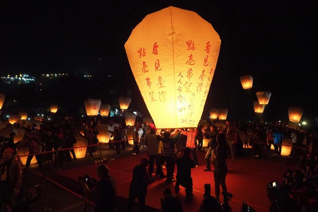 Taiwanese people release a giant sky lantern bearing the words 'Light Up'