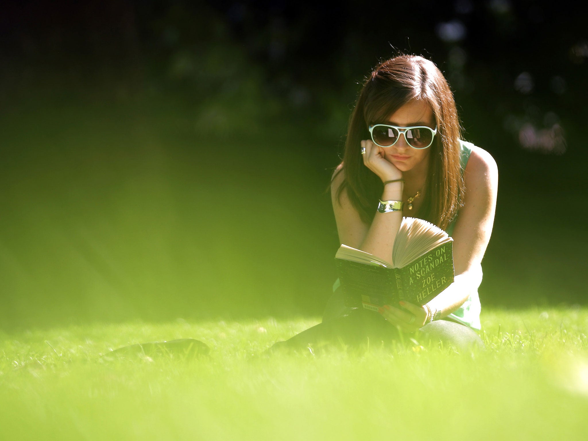 A woman reads a book in the sunshine in Victoria Tower Gardens on September 2, 2011 in London, England.